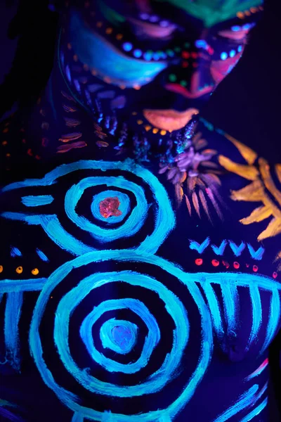 Hombre africano pintado en pintura fluorescente en la cara y el torso musculoso sin camisa — Foto de Stock