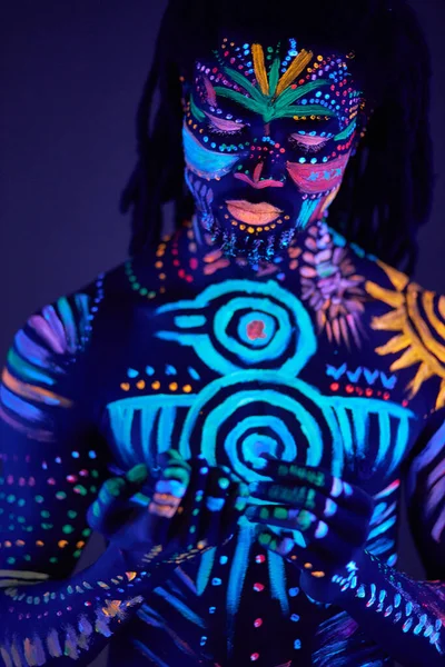 Portret van Afrikaanse man met etnisch patroon, neon make-up in ultraviolet licht — Stockfoto