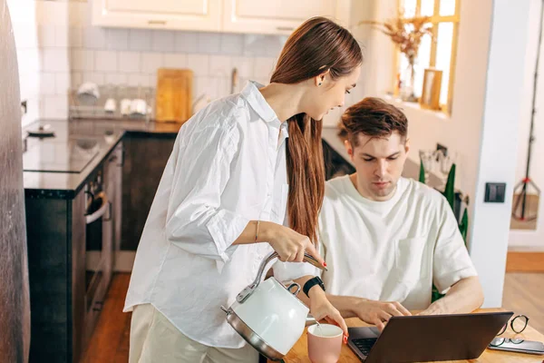 Freundliche Frau behandelt ihren Mann mit leckerem Tee, während er arbeitet — Stockfoto