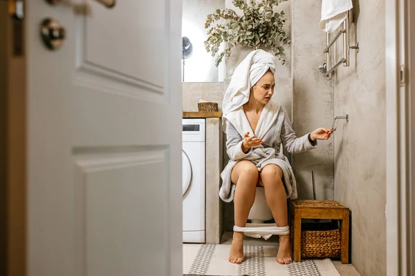 Молода біла жінка сидить на туалеті вранці — стокове фото