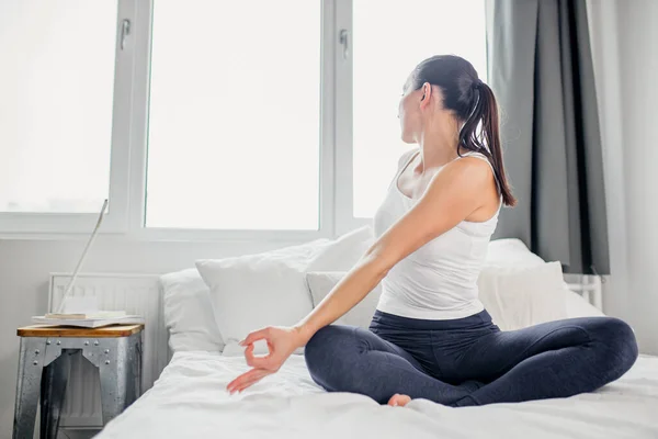 Kvinna meditera och göra övningar på sängen — Stockfoto