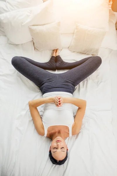 Top view on beautiful young woman lying on bed, in shavasana pose — стоковое фото