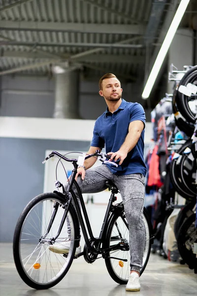 Привлекательный красивый клиент на новом спортивном велосипеде в магазине — стоковое фото