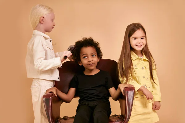 Geconcentreerd albino kind meisje kammen krullend haar van afro jongen geïsoleerd — Stockfoto