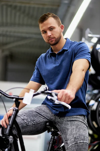 Mağazada yeni spor bisikleti kullanan yakışıklı bir müşteri. — Stok fotoğraf