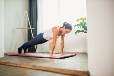 Kadınlar evde egzersiz yaparken şınav çekerler.