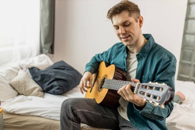 Genç erkek evde gitar çalıyor.