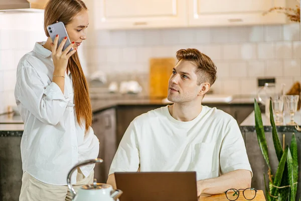 Frau telefoniert, während ihr Mann im Laptop arbeitet, freiberuflich — Stockfoto