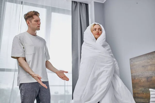 Мужчина разозлился на ленивую девушку в одеяле дома — стоковое фото