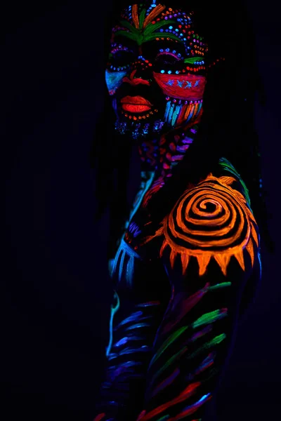 Hombre africano pintado en pintura fluorescente en la cara y el torso musculoso sin camisa — Foto de Stock