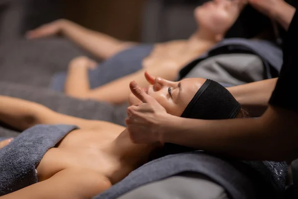 Zwei Frauen erhalten Gesichts- und Nackenmassage im Wellness-Salon — Stockfoto