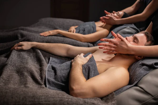 Married couple in spa salon getting facial massage — Stock Photo, Image