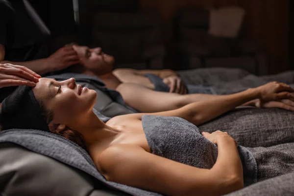 happy couple lying on massage desks in spa salon