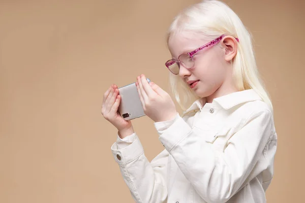 Невинная необычная альбиноса девочка смотрит видео на смартфоне — стоковое фото