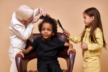 albino child girl combing curly hair of africanamerican boy isolated clipart