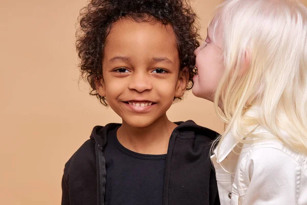 Albino girl tells a secret in the ear of african boy — Stock Photo, Image