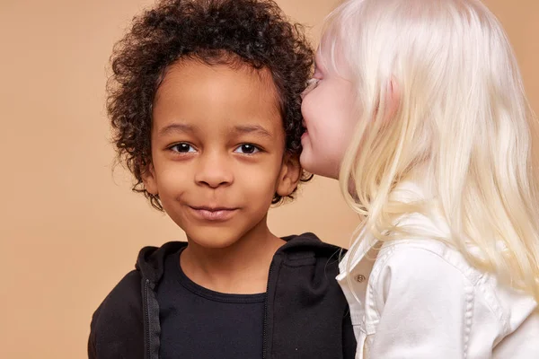 Leende mörkhyade pojke och positiv albino flicka har hemlighet — Stockfoto