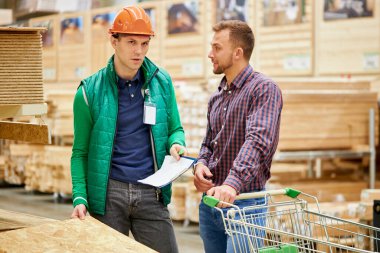 Yakışıklı adam üniformalı bir depocuyla görüşüyor.