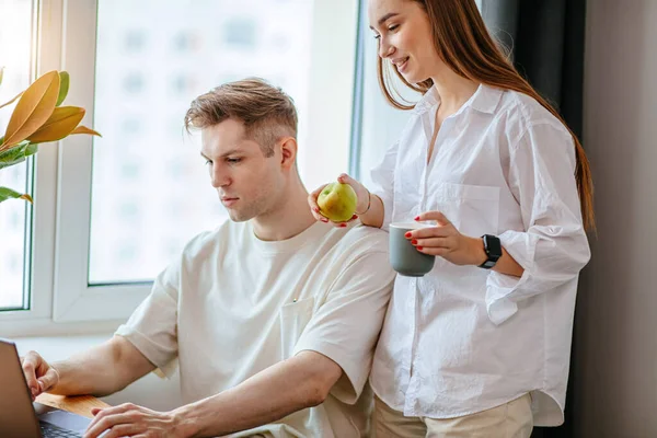 Hübsche Frau unterstützt ihren Mann bei der Arbeit zu Hause — Stockfoto