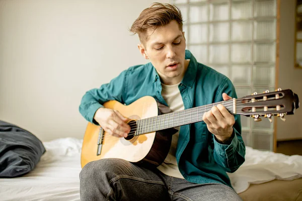 젊은 코카서스 남자 집에서 어쿠스틱 기타를 연주 — 스톡 사진