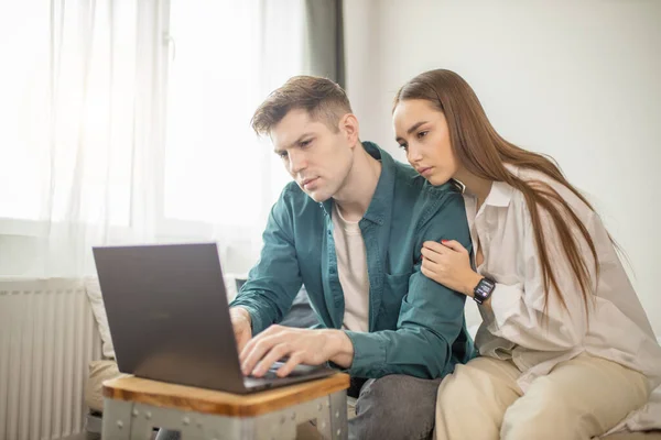 Junge kaukasische Dame immer neben ihrem Mann, der zu Hause arbeitet — Stockfoto