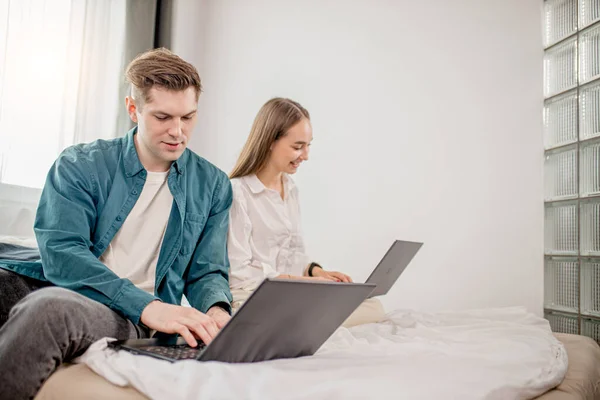 Jovem casal caucasiano trabalham juntos em casa usando laptop — Fotografia de Stock