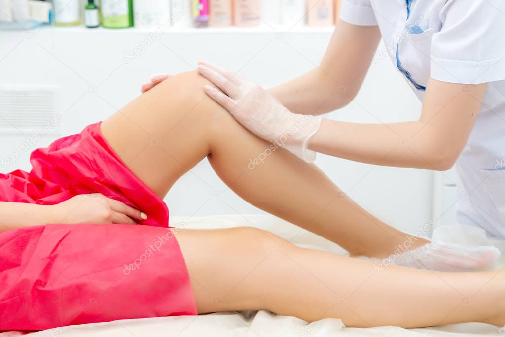 beautician hair removal procedure on the clients feet in beauty parlor