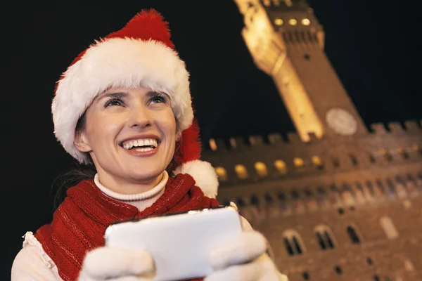 Smiling woman in Christmas hat in Florence, Italy writing sms — Stock fotografie