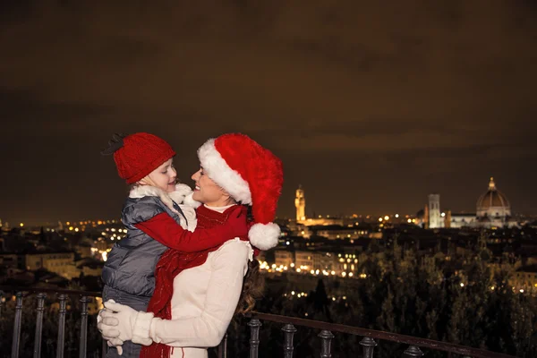 Mamma e bambino sorridenti in cappelli natalizi a Firenze abbracciati — Foto Stock