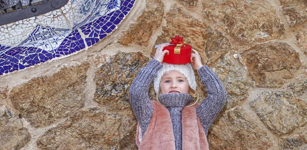 Κορίτσι στο πάρκο Guell, Βαρκελώνη, Ισπανία κρατώντας το δώρο Χριστουγέννων — Φωτογραφία Αρχείου