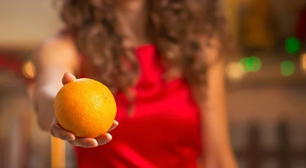 Närbild på glad ung hemmafru ger orange — Stockfoto