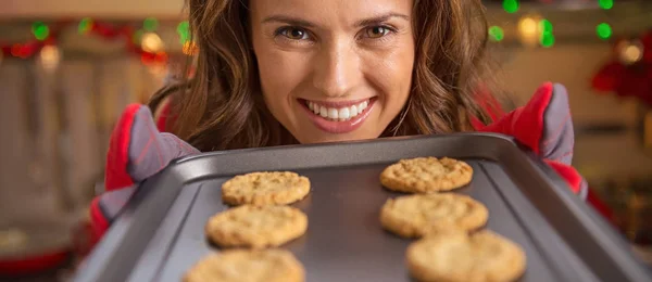 Happy young housewife showing pan with christmas cookies — Stock Photo, Image
