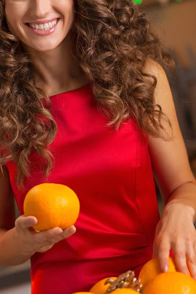 Happy young housewife decorating christmas plate with oranges — Stock Photo, Image