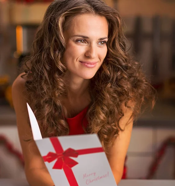 Πορτρέτο της χαρούμενης νεαρής γυναίκας με χριστουγεννιάτικη κάρτα στην κουζίνα — Φωτογραφία Αρχείου