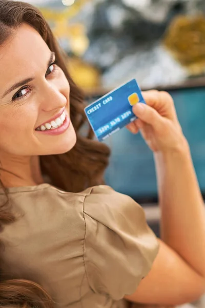 Smiling young woman with credit card using laptop in front of ch — Stock Photo, Image