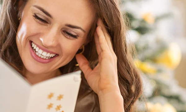 Smiling young woman reading christmas postcard — Stock Photo, Image