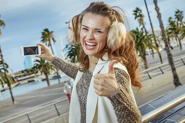 Turista mulher mostrando polegares para cima e tirar foto com smartphone — Fotografia de Stock