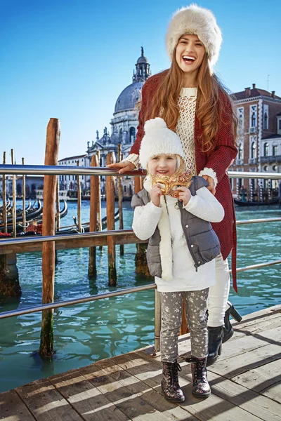 Счастливая мать и ребенок путешественники держа венецианскую маску, Венеция — стоковое фото