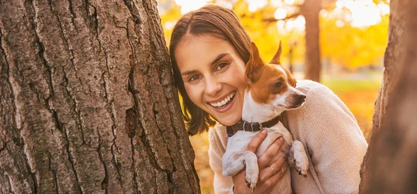 Feliz joven con perro al aire libre en el parque de otoño mirando hacia fuera f — Foto de Stock