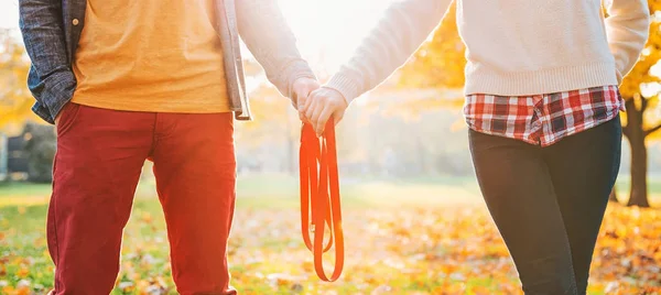 Detailní záběr na mladý pár hospodářství vodítko společně v podzimním parku — Stock fotografie