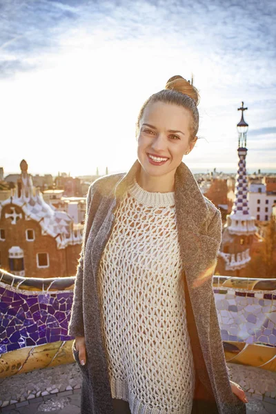 Sonriente mujer de moda en abrigo en el Parque Guell en Barcelona, España —  Fotos de Stock