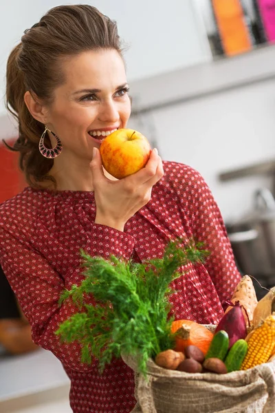 Junge Hausfrau mit Einkäufen vom lokalen Markt isst Apfel — Stockfoto