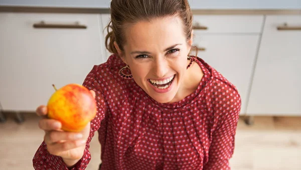Happy woman holding up apple while holding fall vegetables — Stock Photo, Image