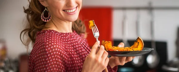 Крупным планом молодая женщина ест запечённую тыкву на кухне — стоковое фото