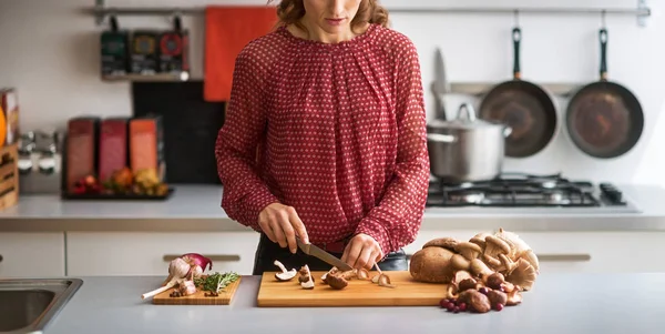 Jonge huisvrouw snijden paddestoelen in keuken — Stockfoto
