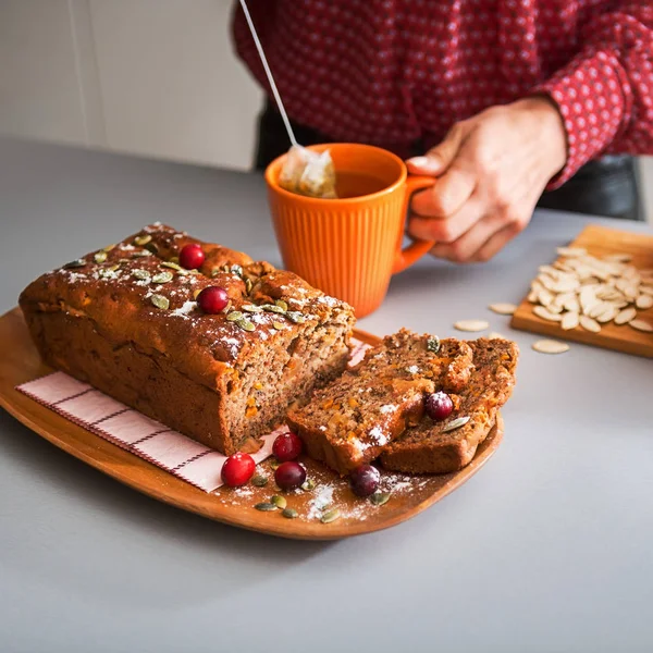 Sliced home-made loaf of pumpkin bread, woman's hands and tea — Stock Photo, Image