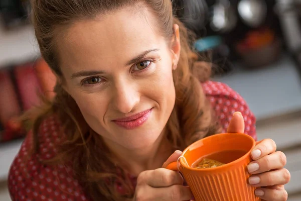 Glückliche junge Hausfrau trinkt Tee in der Küche — Stockfoto