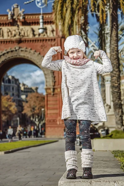 Dítě v blízkosti Arc de Triomf v Barceloně, ve Španělsku ukazuje sílu — Stock fotografie