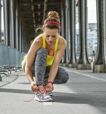 sporcumuz Paris Pont de Bir-Hakeim köprüde, ayakkabı bağcığı bağlama