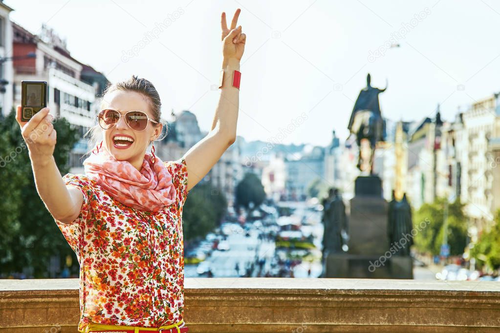tourist woman with digital camera taking selfie in Prague